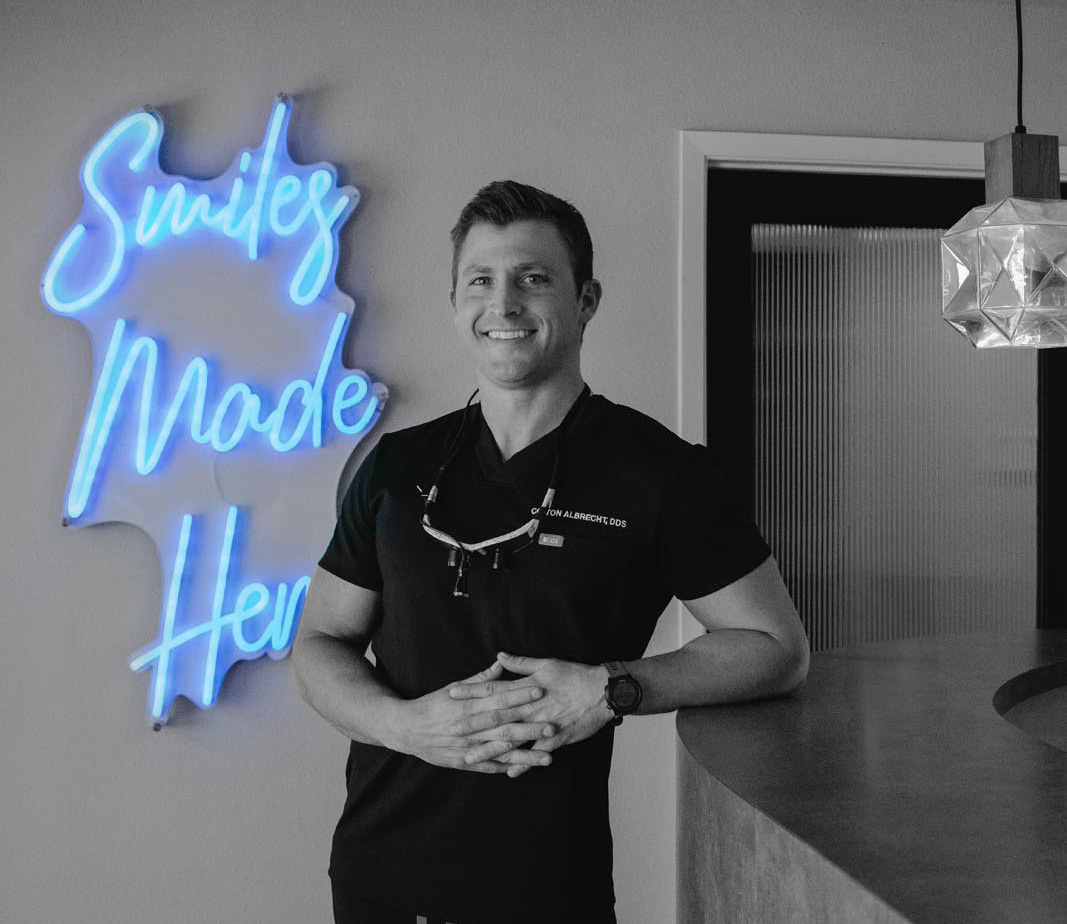 dr. albrecht in front of a sign that says smiles made here